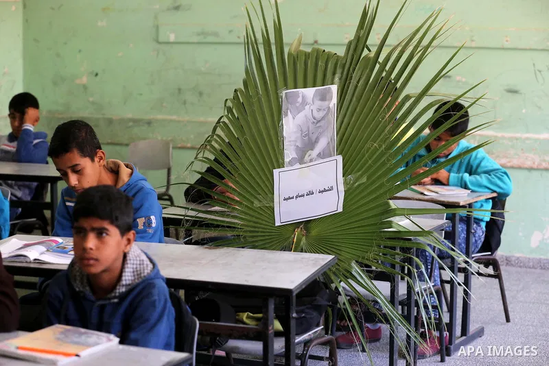 A picture of Palestinian boy Khaled Saed,14, who was killed in an Israeli air strike on the Gaza Strip, is seen on his study seat next to his classmates at a school, in Deir al-Balah in the central Gaza Strip, on October...
