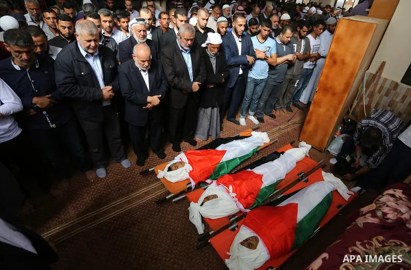 Palestinian Hamas Chief Ismail Haniyeh prays over the bodies of three Palestinian teenagers who were killed in an Israeli air strike on the Gaza Strip during their funeral in Deir el-Balah in central of the Gaza Strip on...