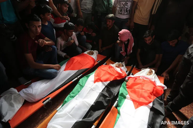Palestinian mourners gather around the bodies of three Palestinian teenagers who were killed in an Israeli air strike on the Gaza Strip during their funeral in Deir el-Balah in central of the Gaza Strip on October 29, 20...
