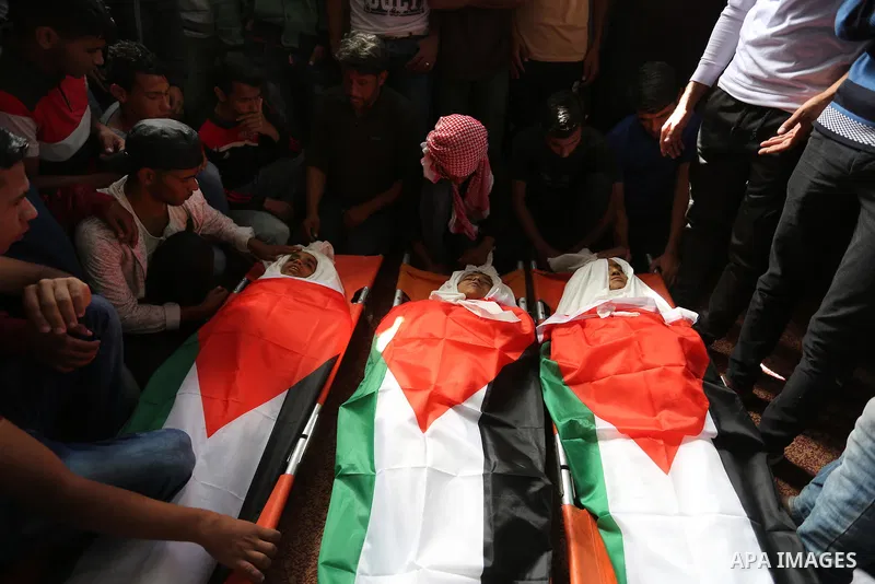 Palestinian mourners gather around the bodies of three Palestinian teenagers who were killed in an Israeli air strike on the Gaza Strip during their funeral in Deir el-Balah in central of the Gaza Strip on October 29, 20...