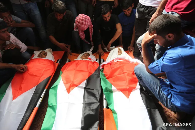 Palestinian mourners gather around the bodies of three Palestinian teenagers who were killed in an Israeli air strike on the Gaza Strip during their funeral in Deir el-Balah in central of the Gaza Strip on October 29, 20...