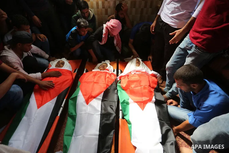 Palestinian mourners gather around the bodies of three Palestinian teenagers who were killed in an Israeli air strike on the Gaza Strip during their funeral in Deir el-Balah in central of the Gaza Strip on October 29, 20...
