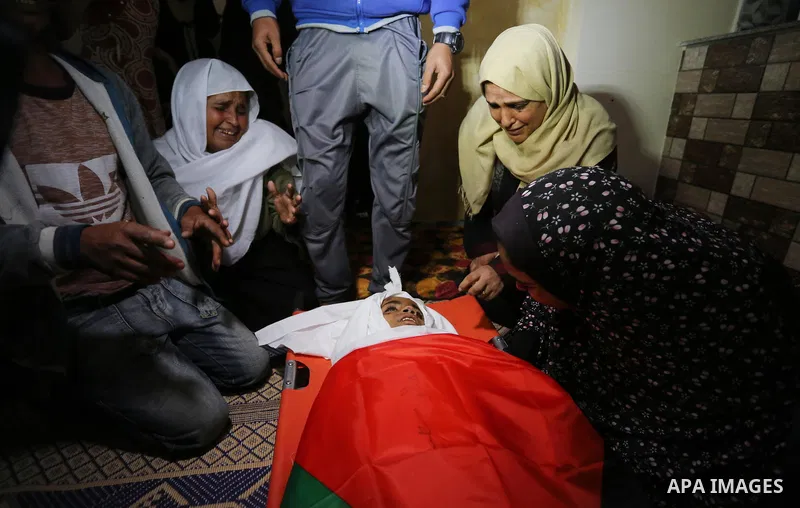 Relatives of Palestinian teenager Khaled Saed, who was killed in an Israeli air strike on the Gaza Strip , mourn over his body during his funeral in Deir el-Balah in central of the Gaza Strip on October 29, 2018. Photo b...