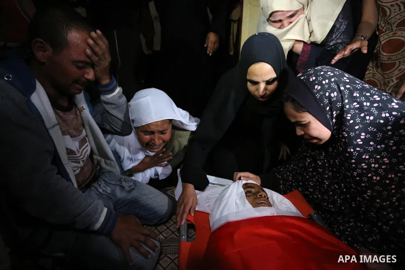 Relatives of Palestinian teenager Khaled Saed, who was killed in an Israeli air strike on the Gaza Strip , mourn over his body during his funeral in Deir el-Balah in central of the Gaza Strip on October 29, 2018. Photo b...