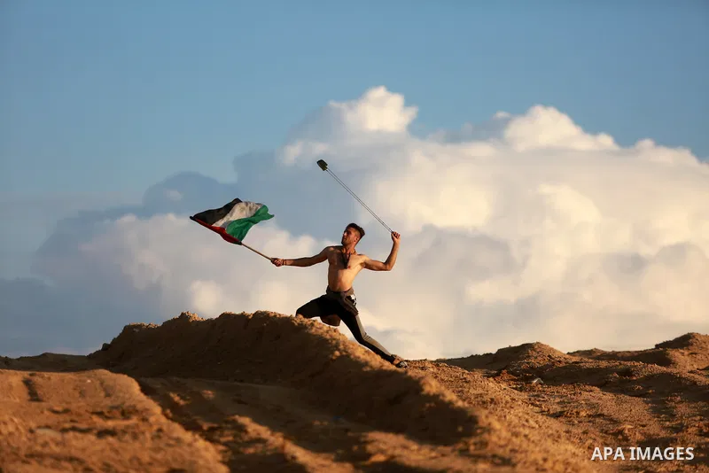 A Palestinian protester uses a slingshot to hurl stones towards Israeli forces during clashes in a demonstration against the Israeli blockade on Gaza Strip, along the Gaza sea barrier on the maritime border with Israel n...