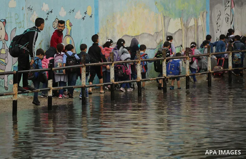 Palestinian students walk in a flooded street during heavy rain in Gaza City on November 10, 2018. Photo by Dawoud Abo Alkas