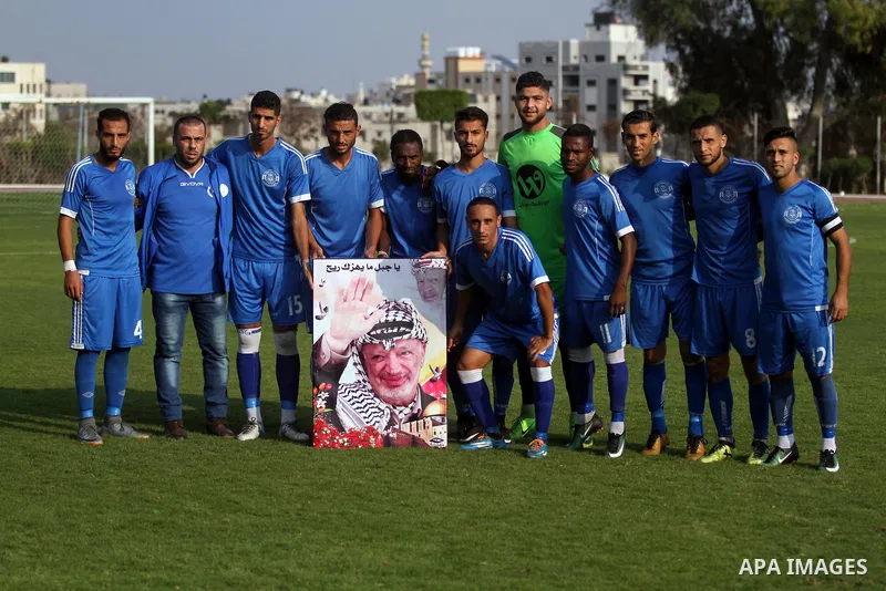Palestinian players of Khadamat al-Shati hold a pictrue depicting late Palestinian leader Yasser Arafat to mark the 14th anniversary of his death, before their a football match with Ahly Beit Hanoun, at Yarmouk Stadium i...