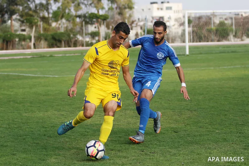 Palestinian players of Khadamat al-Shati (in blue) and players of Ahly Beit Hanoun in (yellow), compete during a a football match at Yarmouk Stadium in Gaza City on November 11, 2018. Photo by Mahmoud Ajjour