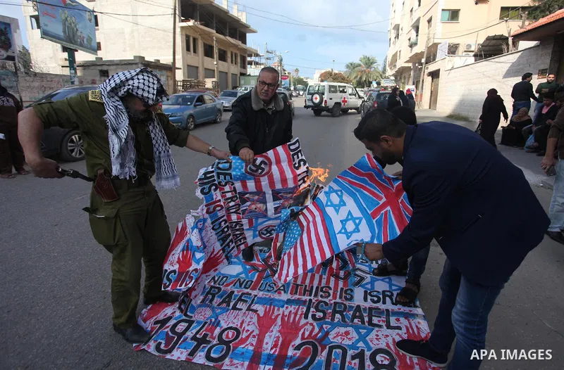 Palestinians burn an Israeli, British and U.S. flags during a protest to show solidarity with Palestinian prisoners held in Israeli jails, in front of Red cross office in Gaza city, on November, 26, 2018. Photo by Mahmou...