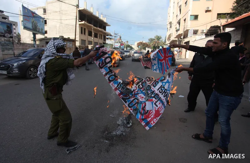 Palestinians burn an Israeli, British and U.S. flags during a protest to show solidarity with Palestinian prisoners held in Israeli jails, in front of Red cross office in Gaza city, on November, 26, 2018. Photo by Mahmou...