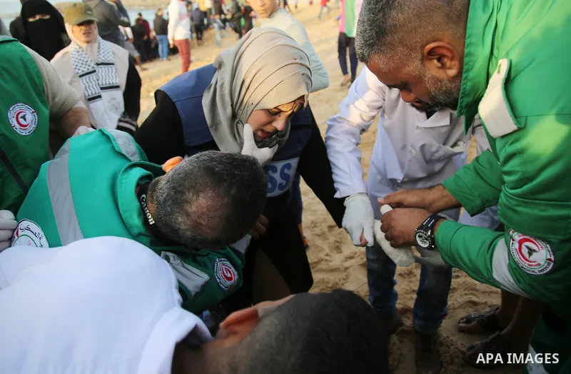 Palestinian medics help a Palestinian female journalist who was wounded during clashes with Israeli forces in a demonstration against the Israeli blockade on Gaza Strip, along the Gaza sea barrier on the maritime border...
