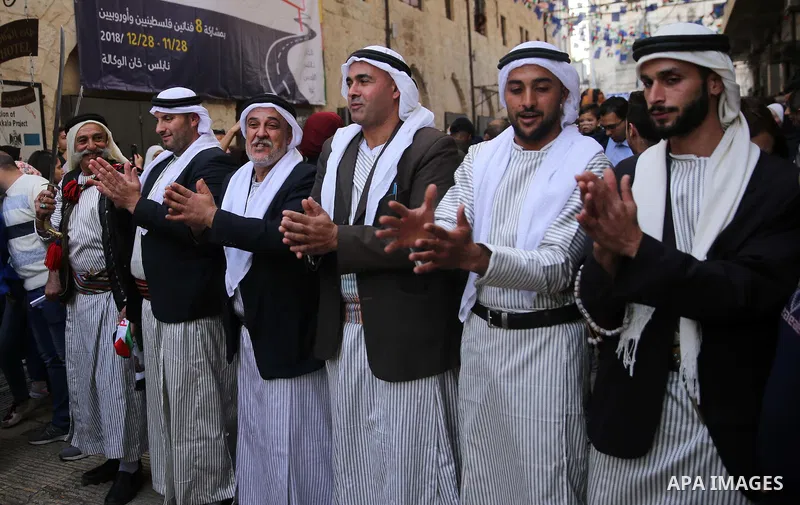 Palestinians wearing traditional costume dance Dabka at street during a street carnival in the West Bank city of Nablus on November 28, 2018. Photo by Shadi Jarar'ah