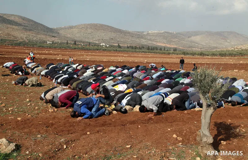 Palestinian protesters attend Friday prayers during clashes Israeli forces against Israeli land seizures for Jewish settlements, in the village of al-Mughayyir, near the West Bank city of Ramallah, on November 30, 2018....