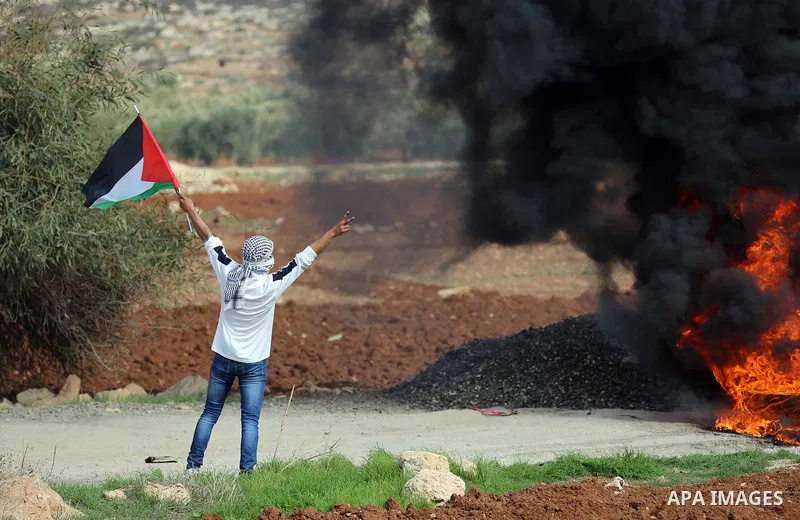 A Palestinian protester reacts from tear gas during clashes Israeli forces against Israeli land seizures for Jewish settlements, in the village of al-Mughayyir, near the West Bank city of Ramallah, on November 30, 2018....