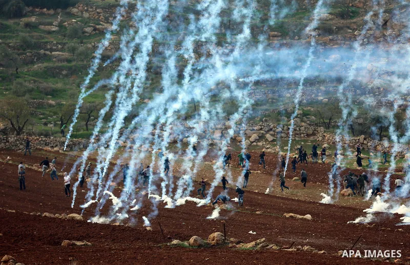 Tear gas canisters are fired by Israeli forces towards Palestinian protesters during a protest against Israeli land seizures for Jewish settlements, in the village of al-Mughayyir, near the West Bank city of Ramallah, on...