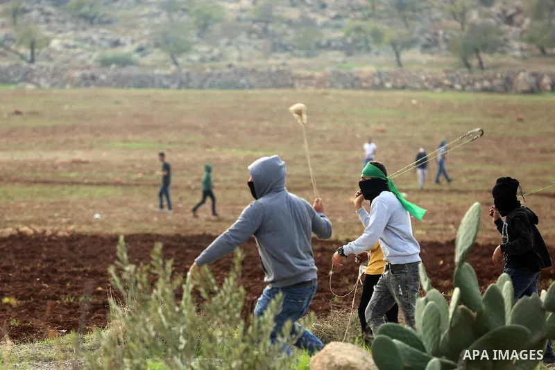 Palestinian protesters hurl stones towards Israeli forces during clashes against Israeli land seizures for Jewish settlements, in the village of al-Mughayyir, near the West Bank city of Ramallah, on November 30, 2018. Ph...