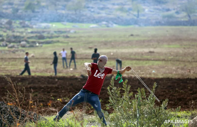 A Palestinian protester reacts from tear gas during clashes Israeli forces against Israeli land seizures for Jewish settlements, in the village of al-Mughayyir, near the West Bank city of Ramallah, on November 30, 2018....