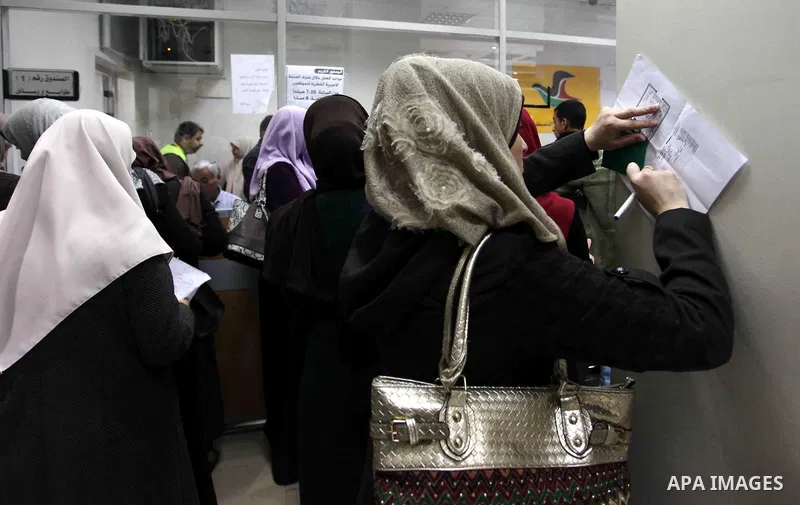Palestinian employees of Gaza strip wait to receive their salaries at a Post Office, in Gaza city, on December 7, 2018. Photo by Mahmoud Ajour