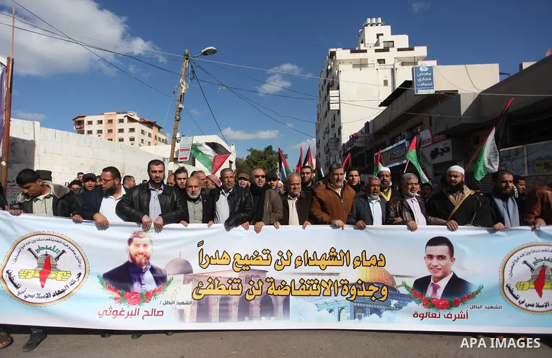 Palestinian members of National and Islamic forces hold banners and Palestine flags during a protest to show solidarity with the martyrs in the West Bank, in Gaza City on December 13, 2018. Israeli forces also killed two...