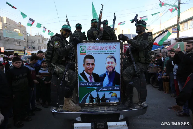 Palestinian members of al-Qassam Brigades, the armed wing of the Hamas movement, display their weapons during a military parade marking the 31th anniversary of Hamas' finding, in Khan Yunis City, southern Gaza strip, Dec...