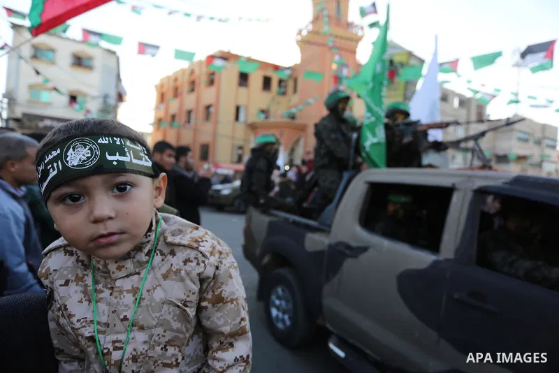 Palestinian members of al-Qassam Brigades, the armed wing of the Hamas movement, display their weapons during a military parade marking the 31th anniversary of Hamas' finding, in Khan Yunis City, southern Gaza strip, Dec...