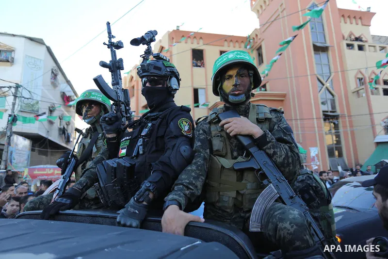 Palestinian members of al-Qassam Brigades, the armed wing of the Hamas movement, display their weapons during a military parade marking the 31th anniversary of Hamas' finding, in Khan Yunis City, southern Gaza strip, Dec...