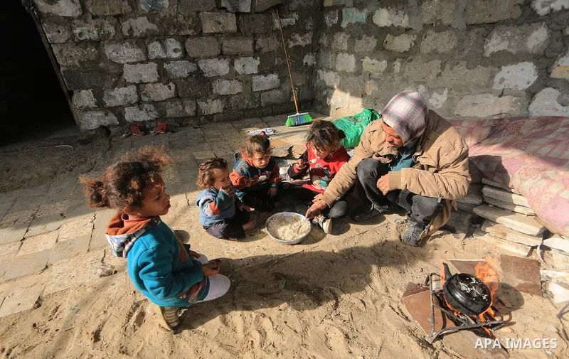 A picture taken on December 20, 2018 shows a Palestinian family eat in front of their dwelling during winter season at Nahr al-Bared refugee camp in Khan Younis in the southern Gaza Strip. Photo by Mahmoud Khattab