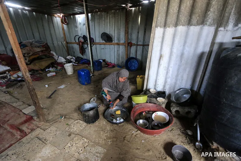 A picture taken on December 20, 2018 shows a Palestinian woman washes dishes in front of her dwelling during winter season at Nahr al-Bared refugee camp in Khan Younis in the southern Gaza Strip. Photo by Mahmoud Khattab