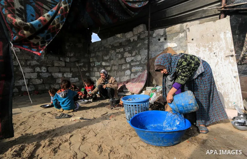 A picture taken on December 20, 2018 shows a Palestinian woman washes laundry in front of her dwelling during winter season at Nahr al-Bared refugee camp in Khan Younis in the southern Gaza Strip. Photo by Mahmoud Khatta...