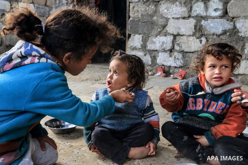 A picture taken on December 20, 2018 shows a Palestinian family eat in front of their dwelling during winter season at Nahr al-Bared refugee camp in Khan Younis in the southern Gaza Strip. Photo by Mahmoud Khattab