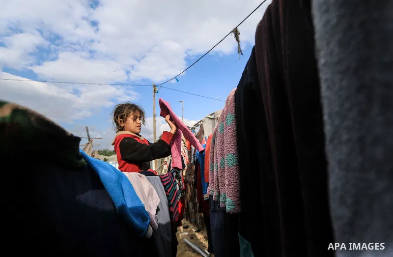 A picture taken on December 20, 2018 shows a Palestinian girl hangs laundry on the rope during winter season at Nahr al-Bared refugee camp in Khan Younis in the southern Gaza Strip. Photo by Mahmoud Khattab