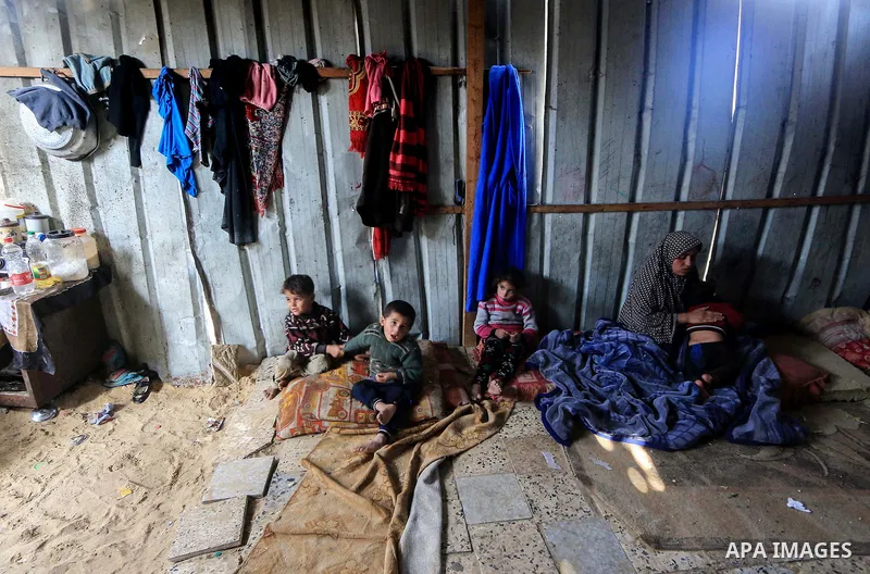 A picture taken on December 20, 2018 shows a Palestinian family sit inside their dwelling during winter season at Nahr al-Bared refugee camp in Khan Younis in the southern Gaza Strip. Photo by Mahmoud Khattab