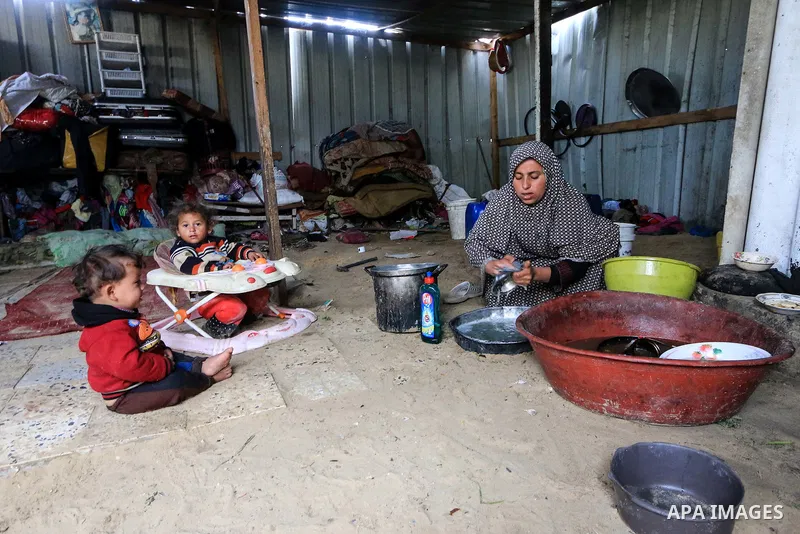 A picture taken on December 20, 2018 shows a Palestinian woman washes dishes in front of her dwelling during winter season at Nahr al-Bared refugee camp in Khan Younis in the southern Gaza Strip. Photo by Mahmoud Khattab