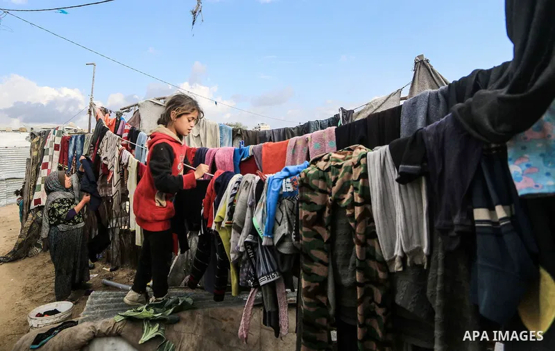 A picture taken on December 20, 2018 shows a Palestinian girl hangs laundry on the rope during winter season at Nahr al-Bared refugee camp in Khan Younis in the southern Gaza Strip. Photo by Mahmoud Khattab