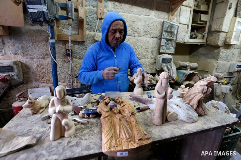 A Palestinian carpenter carves a wooden effigies of the the Holy Family at a workshop in the biblical West Bank city of Bethlehem, a head of the Christmas celebrations on December 23, 2018. Photo by Wisam Hashlamoun