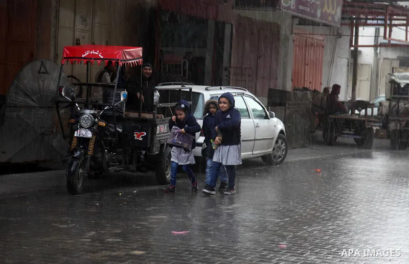 Palestinians walk in a flooded street during a rainy day in Beit Lahia in the northern Gaza Strip on December 27, 2018. Photo by Mahmoud Ajjour