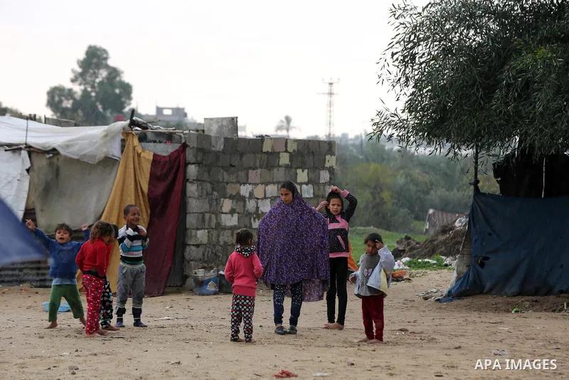 Palestinian children play outside their family's dwelling during a rainy day at Nahr al-Bared refugee camp in Khan Younis in the southern Gaza Strip on December 30, 2018. Photo by Ashraf Amra