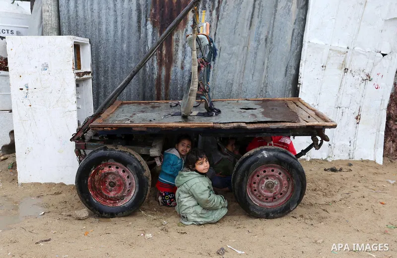 Palestinian children play outside their family's dwelling during a rainy day at Nahr al-Bared refugee camp in Khan Younis in the southern Gaza Strip on December 30, 2018. Photo by Ashraf Amra