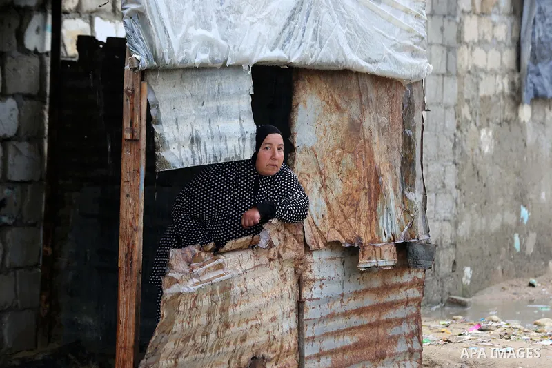 A Palestinian woman stands at her house during a rainy day at Nahr al-Bared refugee camp in Khan Younis in the southern Gaza Strip on December 30, 2018. Photo by Ashraf Amra