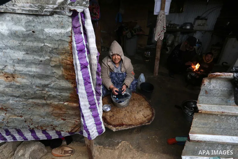 Palestinians sit inside their home during a rainy day at Nahr al-Bared refugee camp in Khan Younis in the southern Gaza Strip on December 30, 2018. Photo by Ashraf Amra