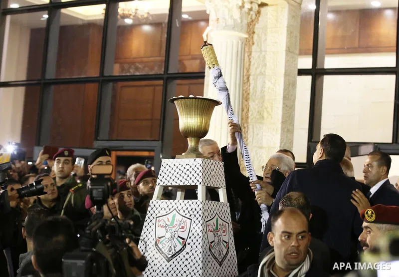 Palestinian President Mahmoud Abbas light a torch during a ceremony marking the 54th anniversary of Fatah's founding, in the West Bank city of Ramallah, on December 31, 2018. Photo by Ahmad Arouri