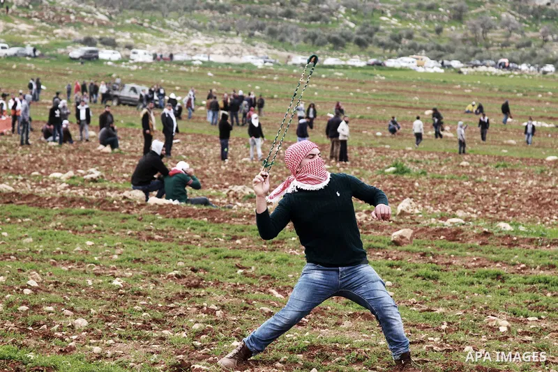 A Palestinian protester hurls stones at Israeli security forces during clashes in al-Mughayar village, near the West Bank city of Ramallah, February 01, 2019. Photo by Ahmad Arouri