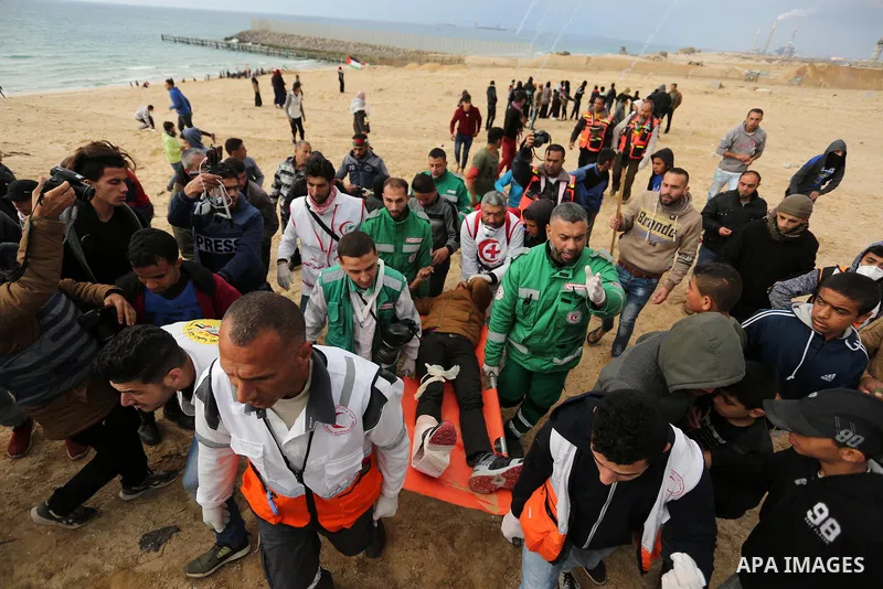 Paramedicals carry a wounded Palestinian protester, who was injured by Israeli security forces at the Gaza-Israel maritime border, during clashes across from the Israeli settlement of Kibbutz Zikim, on February 19, 2019,...