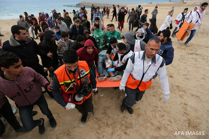 Paramedicals carry a wounded Palestinian protester, who was injured by Israeli security forces at the Gaza-Israel maritime border, during clashes across from the Israeli settlement of Kibbutz Zikim, on February 19, 2019,...
