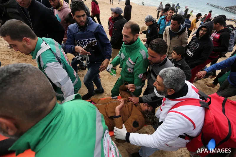 Paramedicals carry a wounded Palestinian protester, who was injured by Israeli security forces at the Gaza-Israel maritime border, during clashes across from the Israeli settlement of Kibbutz Zikim, on February 19, 2019,...