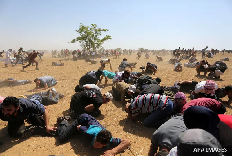 A file photo taken on June 8, 2018 shows Palestinians try to take cover after Israeli forces fired tear gas during "March of the Million for Jerusalem" protests marking the 'Naksa Day' and Al Quds Day (Jerusalem Day) alo...