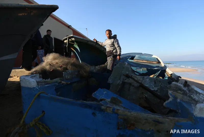 Palestinian fishermen inspect their boat targeted by an Israeli air strike at the beach in Dair Al Balah in the center of Gaza strip on March 10, 2019. Photo by Ashraf Amra