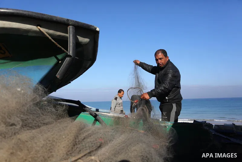 Palestinian fishermen inspect their boat targeted by an Israeli air strike at the beach in Dair Al Balah in the center of Gaza strip on March 10, 2019. Photo by Ashraf Amra