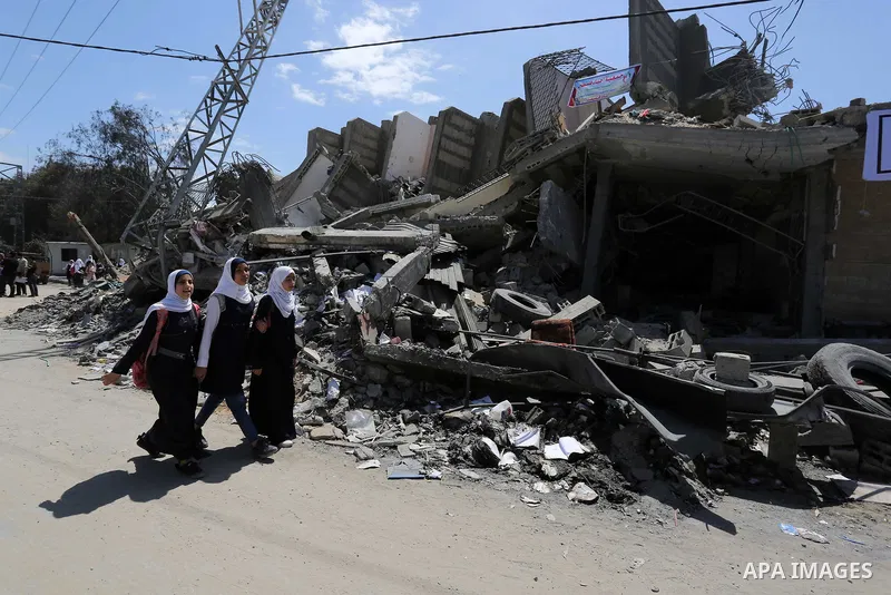 Palestinian students walk past al-Sayeda Roqaya School that demolished in an Israeli airstrike, in Gaza City on May 8, 2019. About 130 residential apartments were completely destroyed, while 700 others were partially des...