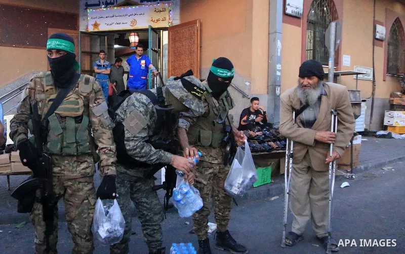 Palestinian militants of Ezzeddin al-Qassam brigades, loyal to Hamas movement, and Al-Quds brigades, loyal to Islamic Jihad movement, distribute dates and water to Palestinians, in Gaza city on May 14, 2019. Qatar will c...